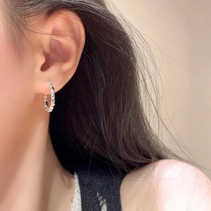 Minimalist silver geometric hoop earrings with textured bead pattern on female model