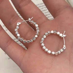 Silver geometric hoop earrings made of small cube beads shown on palm with minimalist style