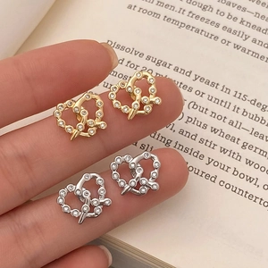Orecchini a lobo minimalisti a cuore con zirconi in oro e argento su sfondo vintage
