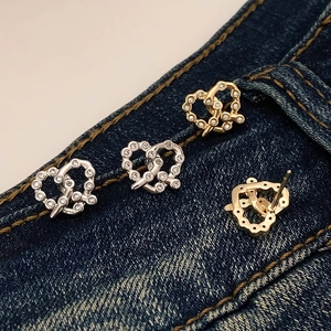 Eleganti orecchini a cuore con zirconi in oro e argento su sfondo di jeans blu