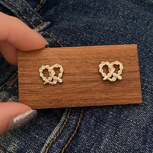 Dettaglio orecchini a cuore pretzel dorati con pavé di zirconi bianchi luccicanti