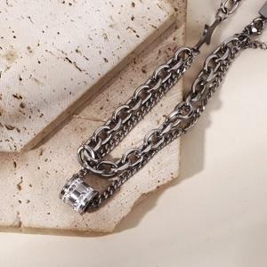 Close-up of double-layered stainless steel chain with a sparkling crystal-set cylinder pendant