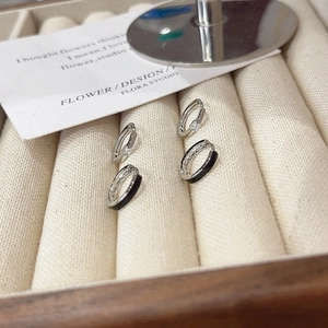 Minimalist black hoops and silver cz earrings set on cream textured jewelry tray
