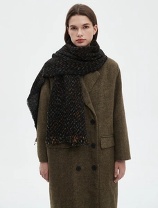 Detailed knit texture of dark multicolored scarf with fringe and green wool coat