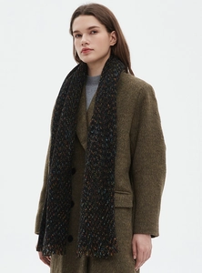 Detail of a textured black scarf with colorful spots paired with a brown tweed coat