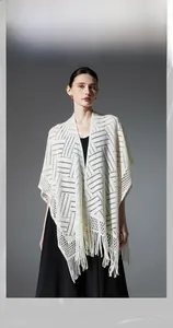 Détail d'un châle en tricot ajouré blanc avec rayures géométriques et longues franges