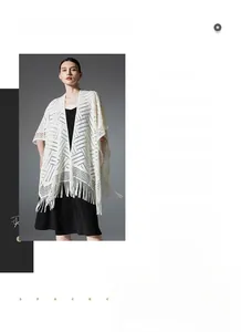 Détail du châle en tricot blanc avec motif géométrique ajouré et longues franges
