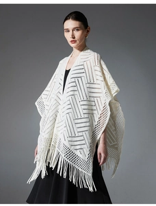 Détail d'un châle en maille blanche avec motifs géométriques et longues franges