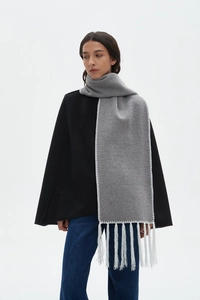 Detail of gray wool scarf featuring white hand-stitched edges and long tassels decoration