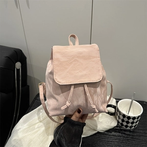 Pink pleated mini backpack with drawstring and flap closure in a casual lifestyle setting