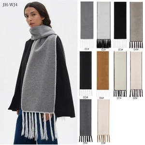 Detail of solid color shawl scarf with long tassels and contrast white edge stitching