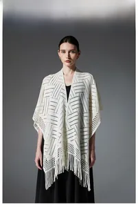 Détail d'un châle en maille blanche avec motifs ajourés et longues franges de style