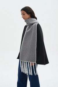 Detail of dark grey winter scarf featuring white contrast stitching and long fringe trim