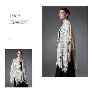 Détail d'un châle en maille blanche avec motifs géométriques ajourés et longs glands