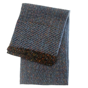 Detailed macro shot of dark grey winter scarf with colorful speckled tweed texture and fringe