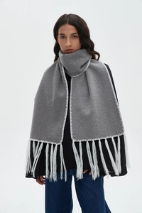 Detail of grey winter scarf featuring white contrast stitching and fine fringe trim