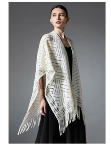 Détail du châle en tricot ajouré blanc avec motifs géométriques et longues franges