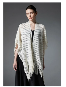 Détail de la texture en tricot géométrique et des longues franges du châle crème