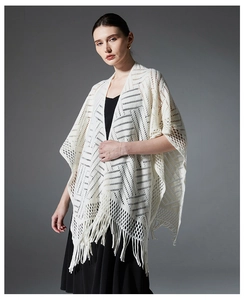 Détail de la maille ajourée géométrique et des longues franges sur châle crème