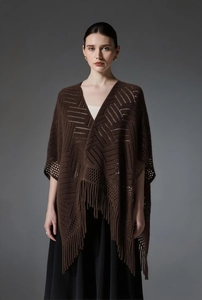 Détails du tricot avec motifs géométriques et longues franges sur ce châle marron