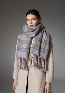 Close-up of thick plaid scarf with lilac and ginger tassels on beige wool coat