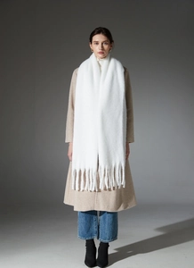 Close-up of white chunky knit scarf showing thick tassels and textured boucle yarn weave