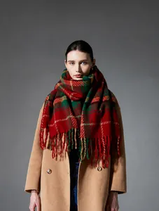 Detailed view of red and green plaid scarf with soft tassels and wool-like texture