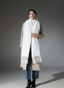 Close-up of thick white boucle knit scarf featuring elegant long fringe tassel details