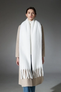 Detailed view of white oversized chunky tassel scarf with soft fluffy knit texture