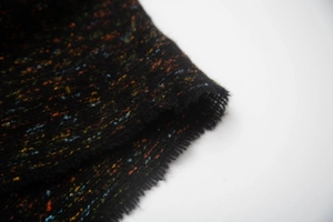 Detail of multi-color thick knit fabric with orange fibers and fringed edge texture