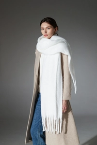 Detailed close-up of soft white boucle scarf featuring thick braided fringe tassels