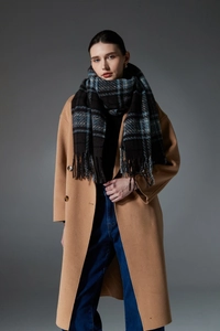 Detail of dark blue checkered scarf with tassels paired with a long camel wool coat