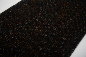 Macro view of colorful flecked texture and fringe on black tweed winter scarf