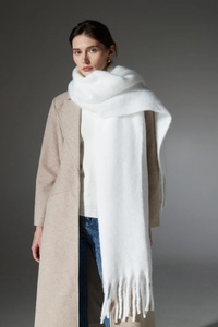 Detail of white chunky knit scarf with long tassels styled on a wool coat outfit