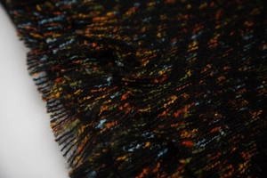Macro detail of multi-color tweed fabric with short fringe on a black scarf