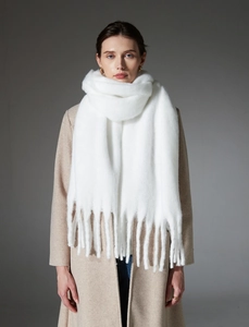 Detailed view of soft thick white mohair-like scarf with long tassels and fuzzy texture