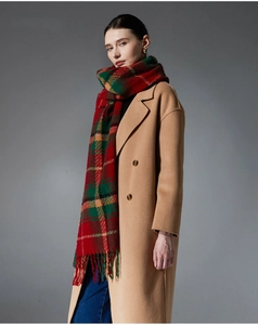 Close-up of red and green plaid scarf with classic tassels on a beige wool coat
