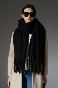 Close-up of thick white boucle knit scarf featuring long textured tassel fringe detail