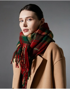 Close-up of red and green plaid scarf texture with long tassels on a camel coat