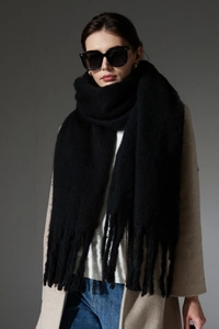 Close-up of thick black mohair-like knit scarf featuring long fringe tassels for winter