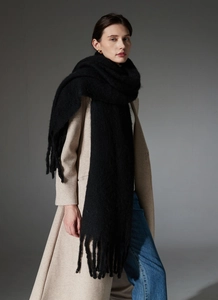 Close-up of thick black boucle scarf with long tassels and fuzzy knit texture