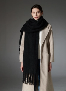 Detail of black thick loop yarn scarf with tassels showing soft knit fiber texture