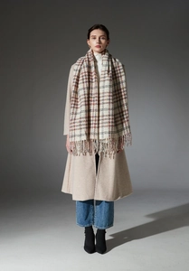 Classic houndstooth plaid scarf with fringe paired with a beige wool coat and denim