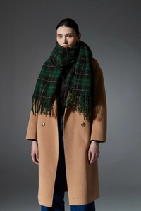 Detail of soft green and black plaid scarf with fringe paired with wool coat
