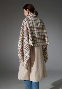 Detail of classic plaid shawl with fringe edges over a wool coat for autumn