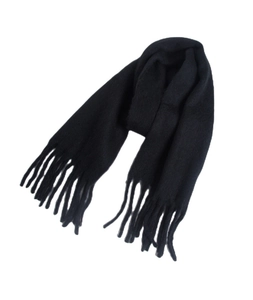 Close-up of thick black winter scarf featuring chunky tassel details and warm knit texture