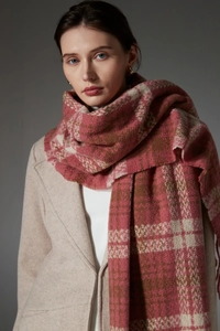 Close-up of thick winter scarf featuring pink and brown plaid pattern with tassel fringe