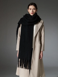 Detail of black thick boucle scarf with long tassels and soft mohair texture