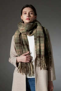 Detail of soft winter scarf featuring dark green plaid pattern and long fringe trim