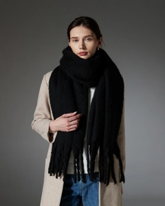 Close-up of thick black boucle scarf with long fringe detail on winter wool coat